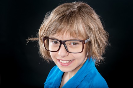 Emotional portrait of attractive caucasian little student girl with eyeglasses. Funny cute smiling child looking at camera on black background.の写真素材