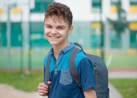 Schoolchild go to school with backpack. Cute child - teen boy with bag against the background of...
