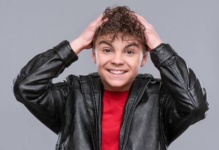 Portrait of a Handsome brutal Teen Boy in a black Leather Jacket. Surprised Smiling fashion Child...