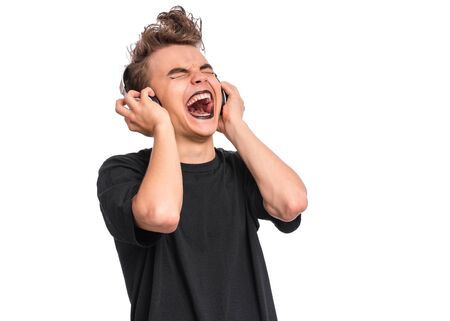 Rebellious happy teen boy with headphones, isolated on white background. Cheerful child listening to music and singing song. Emotional portrait of teenager in style of punk goth enjoying music.の写真素材