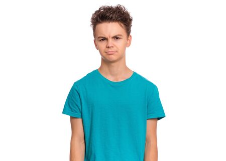 Upset handsome caucasian Teen Boy in blue t-shirt, isolated on white background. Teenager looking at camera. Unhappy child - close-up portrait.の写真素材