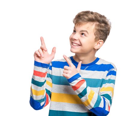 Half-length emotional portrait of caucasian teen boy. Funny teenager pointing and looking upwards while smiling, isolated on white background. Handsome happy child pointing upの写真素材