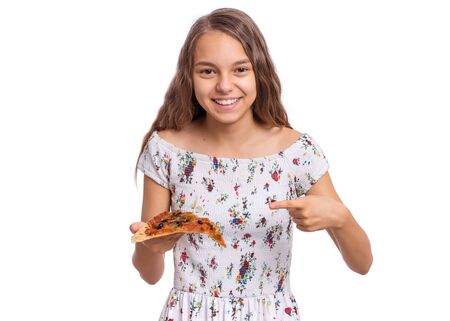 Happy beautiful young teen girl holds slice of pizza. Portrait of child with delicious Italian pizza, isolated on white background. Girl eating fast food.の写真素材