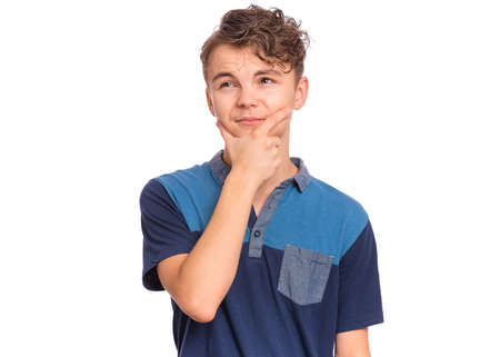 Pensive serious young man in casual touching chin and looking at cameraの写真素材