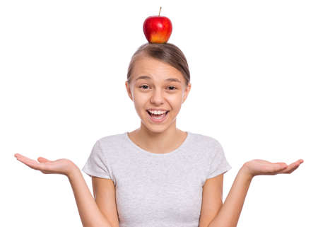 Happy beautiful young teen girl with apple on head, isolated on white backgroundの写真素材
