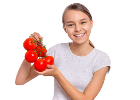 Beautiful young teen girl holding fresh tomatoes, isolated on white backgroundの写真素材