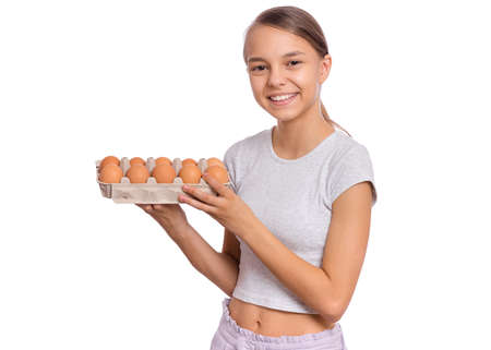 Happy cute teen girl holding brown eggs in box, isolated on white background