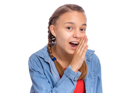 Happy teenage girl whispers, says something, covering her mouth with a palm, isolated on white backgroundの写真素材