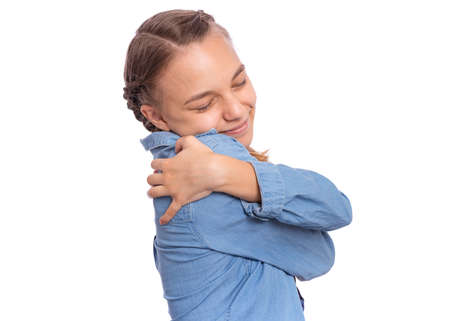 Portrait of calm cheerful teenage girl hug herself, isolated on white backgroundの写真素材