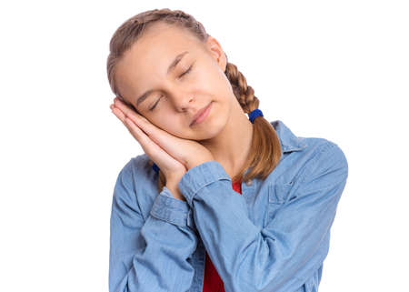 Beautiful teenage girl posing sleeping with folded hands under cheek, isolated on white backgroundの写真素材