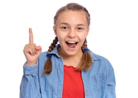 Happy teenage girl pointing up, gesturing idea or doing number one gesture, isolated on white backgroundの写真素材