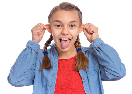 Beautiful crazy teenage girl makes funny face and sticks out tongue, plays fool, being in good mood, isolated on white backgroundの写真素材