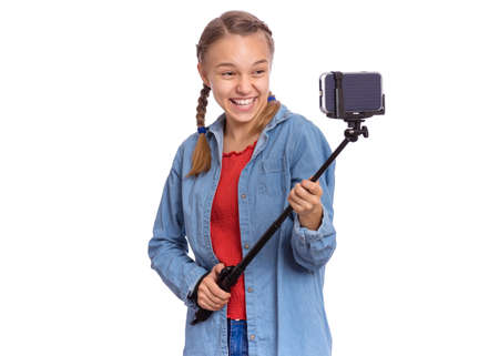 Beautiful teenage girl holds with selfie stick in her hands, isolated on white backgroundの写真素材