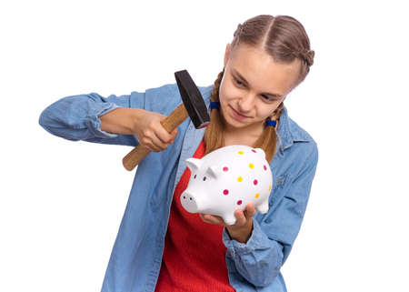 Beautiful teenage girl holds a piggy bank and a hammer in her hands, isolated on white backgroundの写真素材