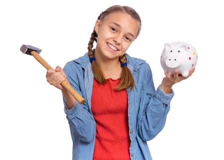Beautiful teenage girl holds a piggy bank and a hammer in her hands, isolated on white backgroundの写真素材