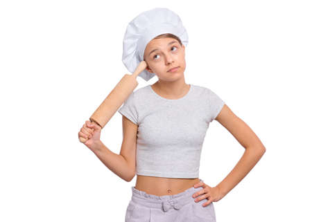 Girl in a chefs hat with emotions holding a rolling pin isolated on a white background.の写真素材