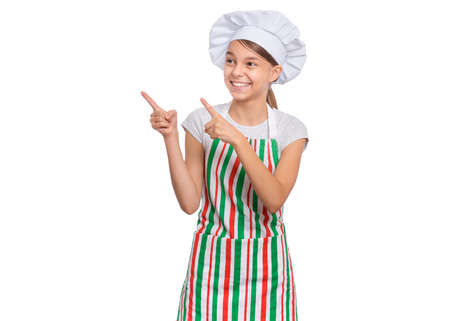 Happy teenage girl wearing chef hat in apron with emotions showing signs with hands, isolated on a white background.の写真素材