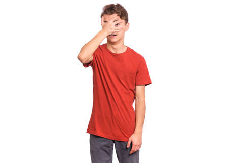 Handsome teen boy with sad expression covering face with hands while crying, isolated on white backgroundの写真素材