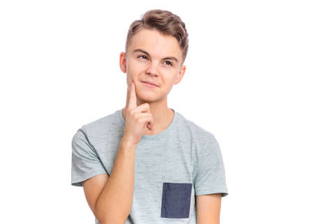 Pensive serious young man in casual touching chin and looking at cameraの写真素材