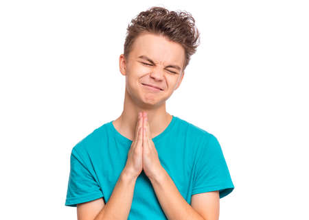 Handsome teen boy with hands folded in prayer hoping for better, isolated on white backgroundの写真素材