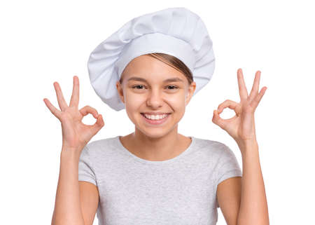 Happy teenage girl wearing chef hat with emotions showing signs with hands, isolated on a white background.の写真素材