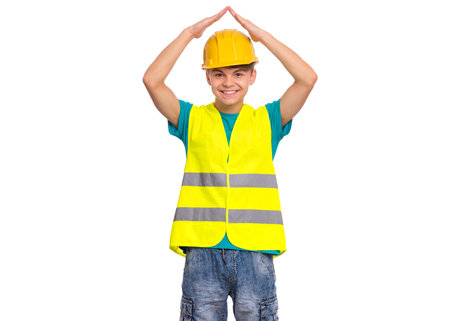 Emotional portrait of handsome teen boy wearing safety jacket and yellow hard hat. Happy child looking at camera, isolated on white background. Funny cute guy - constructionの写真素材