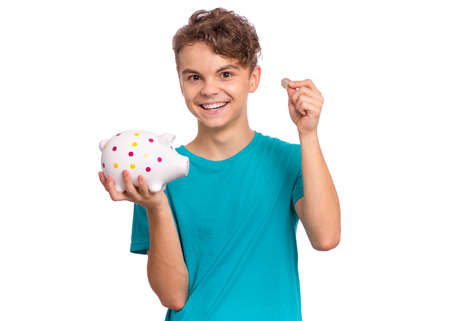 Portrait of teen boy holding Piggy Bank. Cute caucasian young teenager isolated on white background. Saving Money concept. Crazy funny child about to break his piggybankの写真素材