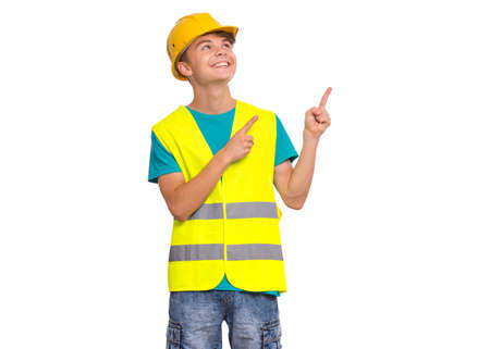 Emotional portrait of handsome teen boy wearing safety jacket and yellow hard hat. Happy child looking at camera, isolated on white background. Funny cute guy - constructionの写真素材