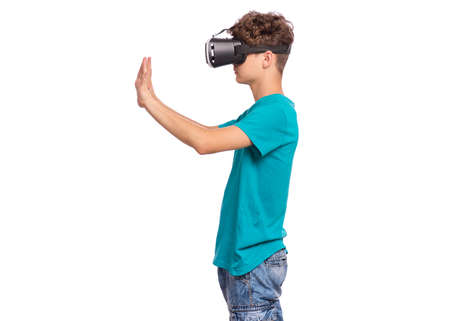 Portrait of young caucasian teen boy using virtual reality goggles. Funny teenager looking in VR glasses. Handsome child experiencing 3D gadget technology, isolated on white backgroundの写真素材