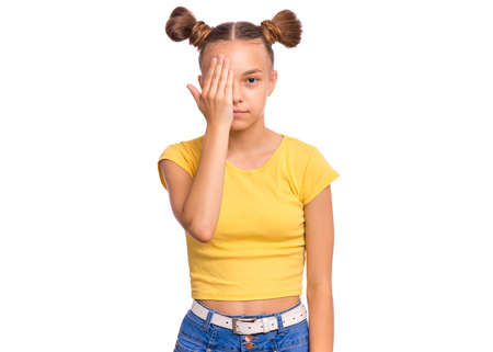 Happy teenage girl looks with one eye while covering his other eye with his hand, isolated on white backgroundの写真素材