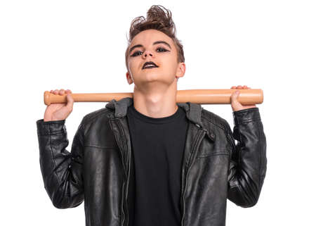 Rebellious teen boy dressed in black, isolated on white background. Young teenager in style of punk goth wearing leather jacket, holding wooden bat. Problems of transitional ageの写真素材