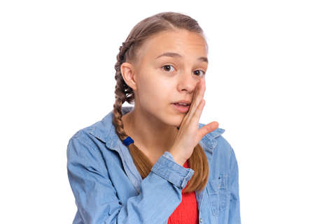 Happy teenage girl whispers, says something, covering her mouth with a palm, isolated on white backgroundの写真素材