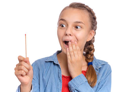Teen girl holding big match, isolated on white background. Smiling child plays with matches. Fire dangerous conceptの写真素材