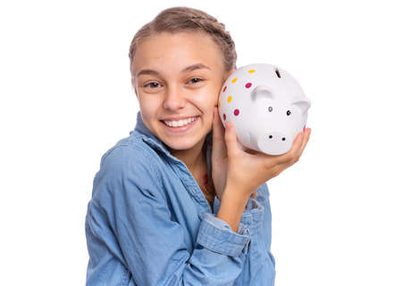 Beautiful teenage girl holds a piggy bank in her hands, isolated on white backgroundの写真素材