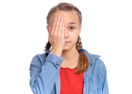Happy teenage girl looks with one eye while covering his other eye with his hand, isolated on white backgroundの写真素材