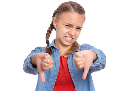 Portrait of teen girl giving thumbs down gesture looking with negative expression and disapproval, isolated on white backgroundの写真素材