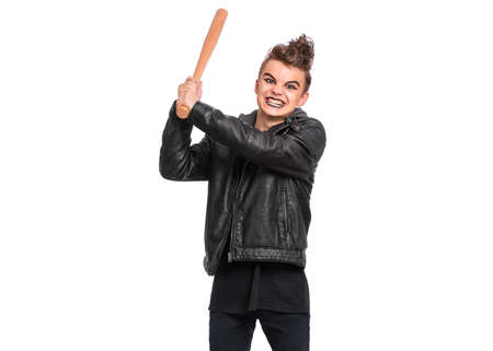Rebellious teen boy dressed in black, isolated on white background. Young teenager in style of punk goth wearing leather jacket, holding wooden bat. Problems of transitional ageの写真素材