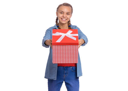 Portrait of Teen girl holding red gift box, isolated on white background. Happy child with birthday or christmas present. Cute caucasian young teenager smiling and looking at cameraの写真素材