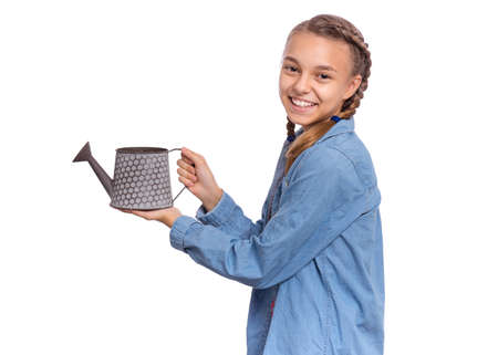 Portrait of teen girl holds small garden watering can, isolated on white background. Beautiful young female student with watering can. Happy smiling childの写真素材