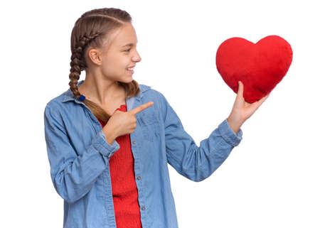 Valentines Day concept. Portrait of cute teen girl with red heart, isolated on white background. Smiling child holds symbol of love, family, hope. Cute caucasianの写真素材