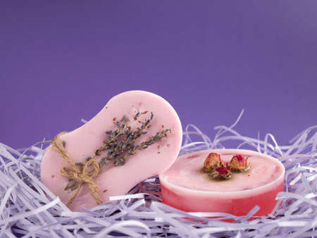 Natural soap bars with rose and lavender flavors with copy space on purple background. Spa and skin care productsの写真素材