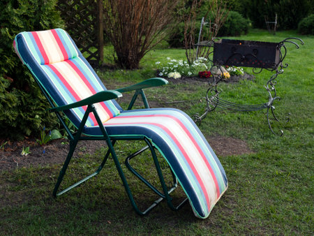 Chaise longue and alit coals in chargrill. In expectation of barbecue. Idyllic landscapeの写真素材