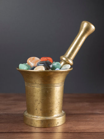 Multicolored stones and minerals in the old mortar with pestle. Concept of lithotherapy, ancient medicine and alchemyの写真素材