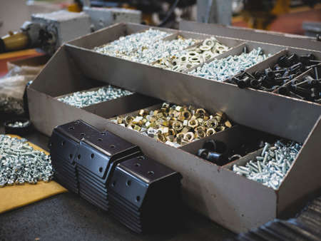 Different types of fasteners on the worker's table. Work place at the assembling shop. Bolts and...