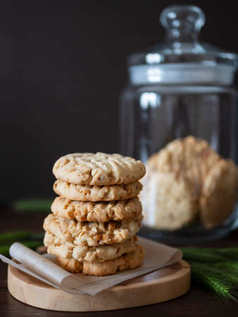 Homemade nut cookies on a wooden board, spikelets and a glass biscuit jar on the background. Upright...