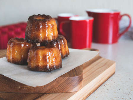 Caneles de Bordeaux on a wooden board. Famous French pastry. Coffee or tea cup accompanimentの写真素材