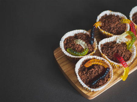 Halloween chocolate cupcakes with jelly worms coming out of soil. Food for children party. Holiday funny snacksの写真素材