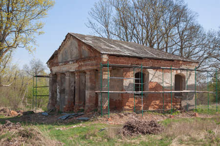 The scaffolding on the of a former manor house or a temple. Fixing the brick building. Concept of reconstruction, rebirth. Renovation worksの写真素材