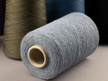 Cones of neutral tones threads. Bobbins of cotton, woolen or synthetic yarn for textile...