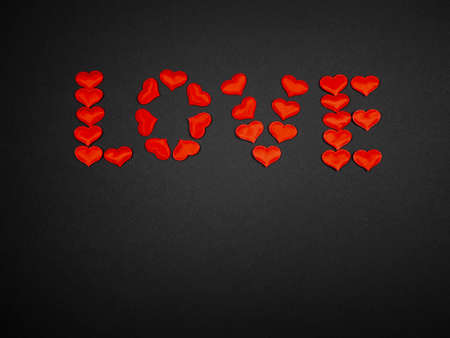 Word Love made from small red hearts on a black background. Concept of feelings, romance, Valentine's Dayの写真素材